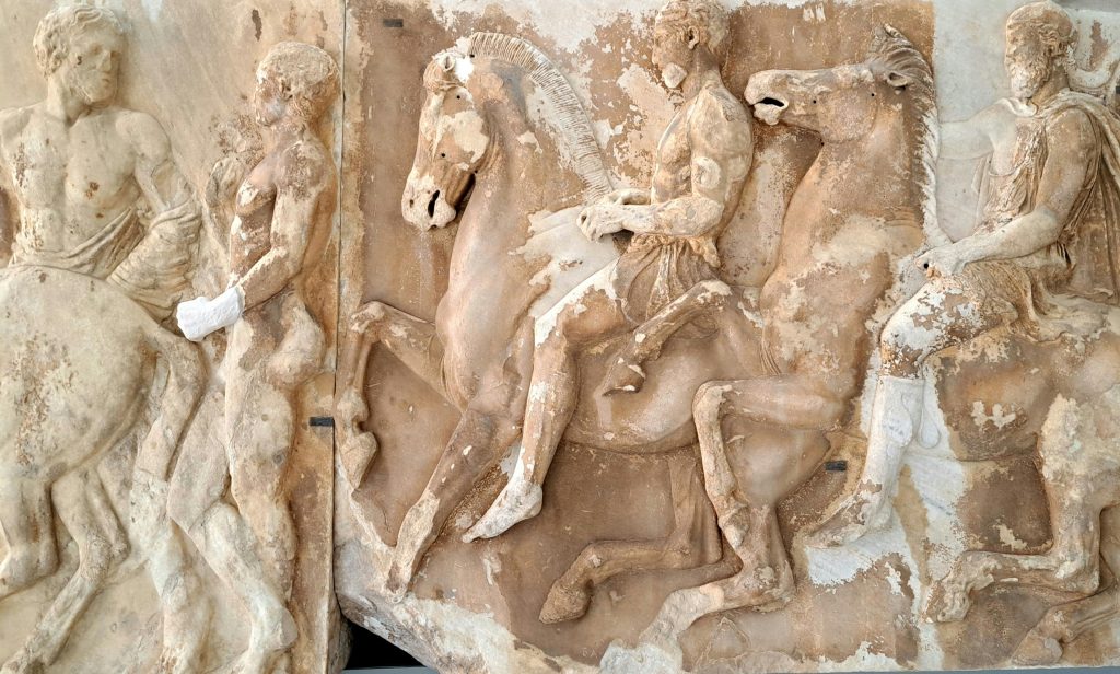 Ancient Greek marble relief depicting horsemen and figures, showing classical art and mythology