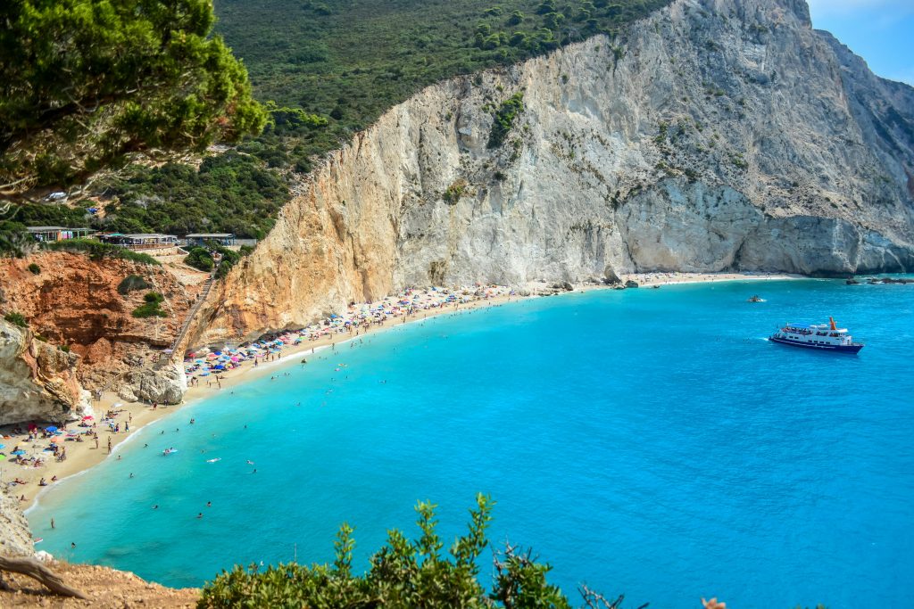 Porto Katsiki beach on Lefkada island with golden cliffs, turquoise sea, and sunbathers on the sand.