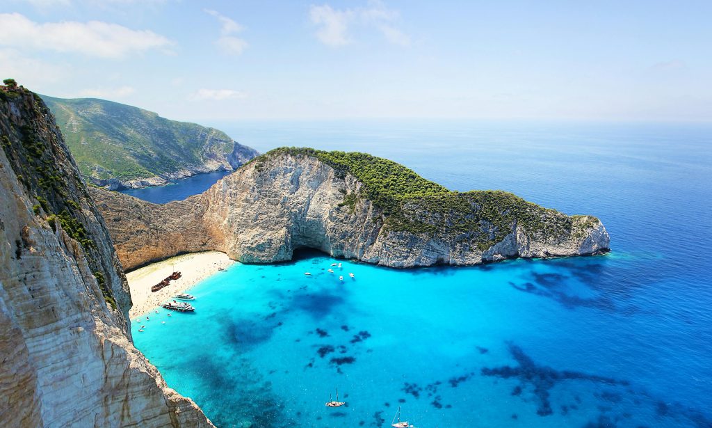 Navagio Beach, also known as Shipwreck Beach, is surrounded by towering white cliffs and vivid blue waters in Zakynthos, Greece.