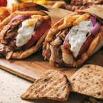 Greek souvlaki, gyros wrapped in pita breads on a wooden background